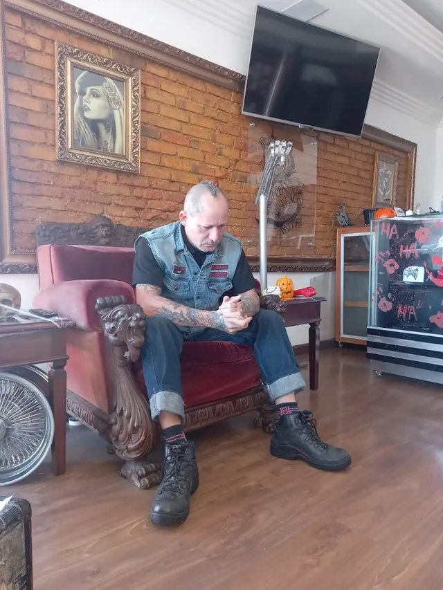 Ambiente com poltrona de veludo vermelho, parede de tijolos e quadro de arte